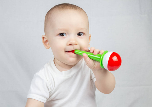 Foto eines acht Monate alten Babys mit Rassel im Mund - Foto, Bild