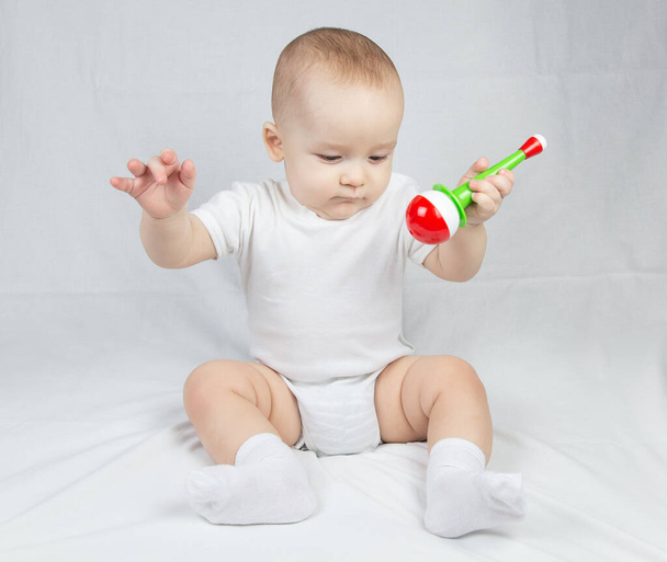 Bild eines acht Monate alten Babys mit Rassel im Mund - Foto, Bild