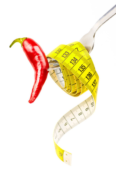 Fork with measuring tape and chili pepper. Concept of natural weight loss. Close up, selective focus. - Photo, image