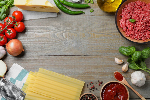 Frame made of fresh lasagna ingredients on grey wooden table, flat lay. Space for text - Φωτογραφία, εικόνα