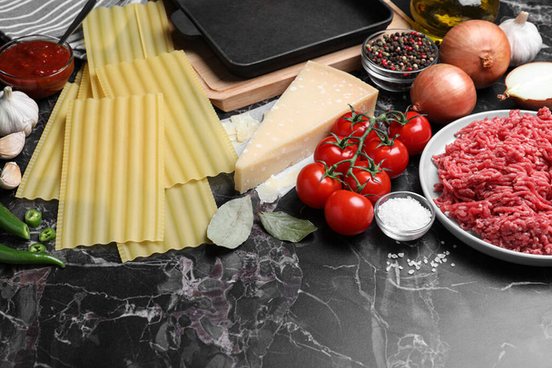 Fresh ingredients for lasagna on black marble table - Photo, image