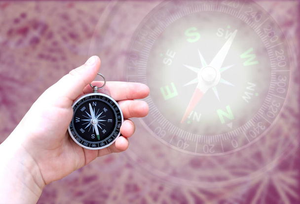 Круглый компас в руке на абстрактном фоне как символ туризма с компасом, путешествия с компасом и активного отдыха с компасом - Фото, изображение