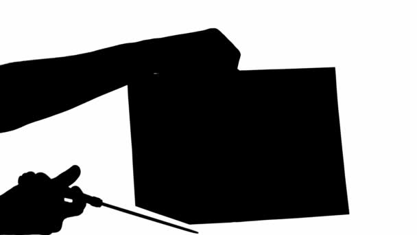 Silhouette of man cutting paper sheet on white background - Footage, Video