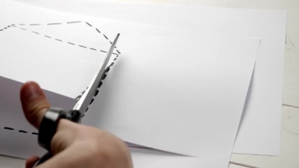 Uomo taglio foglio di carta con forma disegnata di casa, primo piano - Filmati, video
