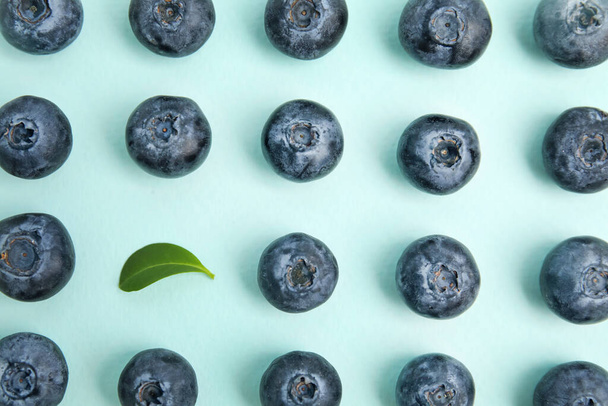 Fresh ripe blueberries and leaf on light blue background, flat lay - Photo, image