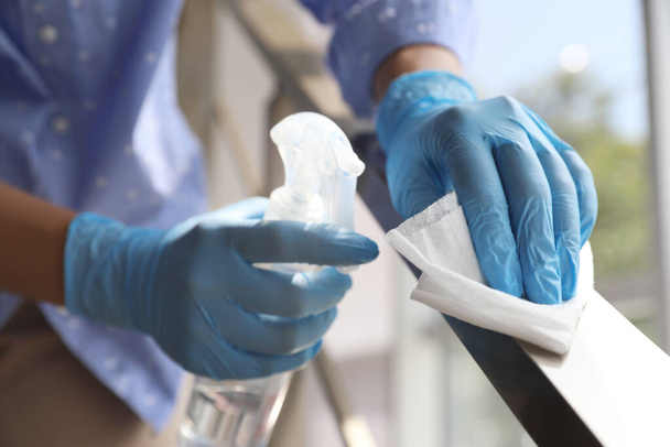 Woman in latex gloves cleaning railing with wet wipe and detergent indoors, closeup - Foto, Imagem