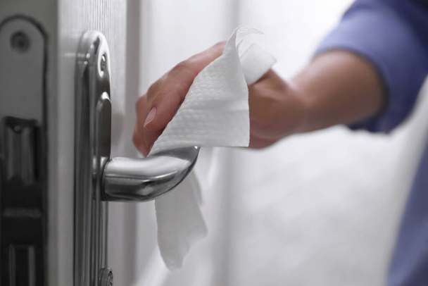 Woman cleaning door handle with wet wipe indoors, closeup - Foto, Bild