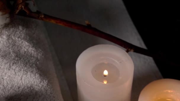 Krásná lázeňská kompozice s bavlněnými květy, ručníky a vonnými svíčkami na tmavém pozadí, detailní záběr - Záběry, video