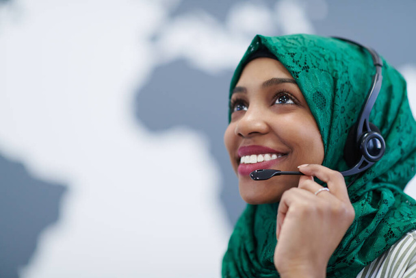 African muslim female with green hijab scarf customer representative business woman with phone headset helping and supporting online with customer in modern call centre - Фото, изображение