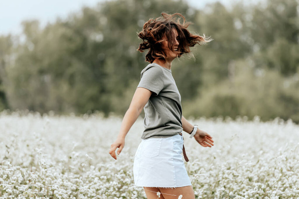 Portré egy gyönyörű fiatal nő fut át a területen fehér virágok, élvezi a napot, egy napsütéses nyári napon. A gyermek és a természet egységének fogalma, békés hangulat, környezeti élet - Fotó, kép