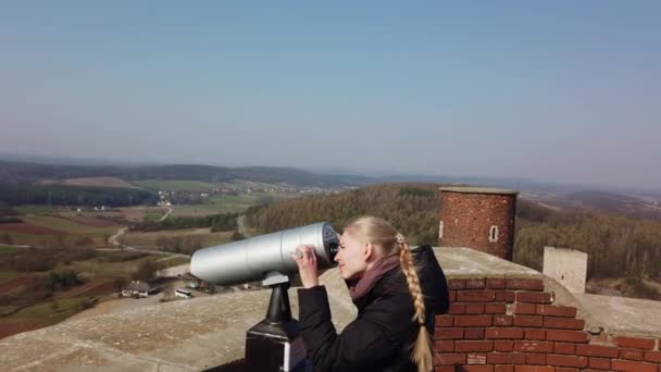 Vonzó női utazó távcsövet használ, hogy körülnézzen a völgyben a régi vár közelében - Felvétel, videó