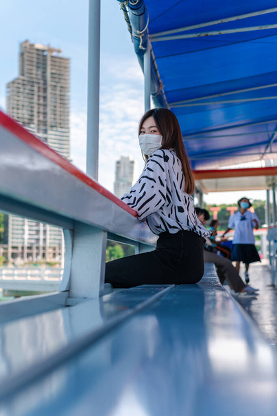 Mulheres tailandesas usando uma máscara para evitar o surto de covid-19, Uma nova proteção turística normal contra a epidemia em 2020, Mulheres sentadas em um barco de passageiros flutuando no mar, Conceito de covid-19 pré
 - Foto, Imagem