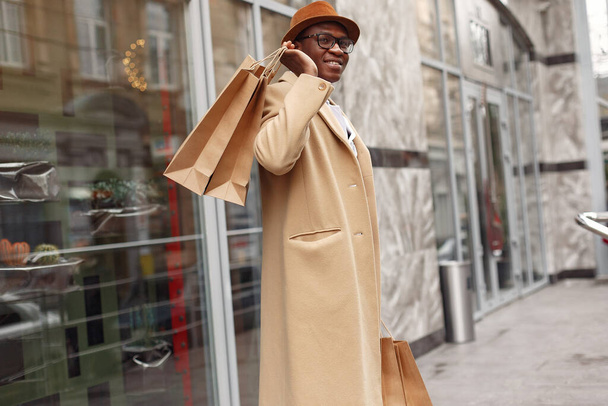 Stylish black man in a city with shopping bags - 写真・画像
