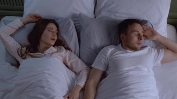 Fiatal irritált férfi az ágyban horkoló feleséggel - Felvétel, videó