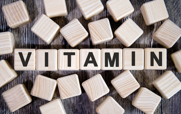 VITAMIN - medical concept, text on wooden cubes and many cubes around on a dark background - 写真・画像