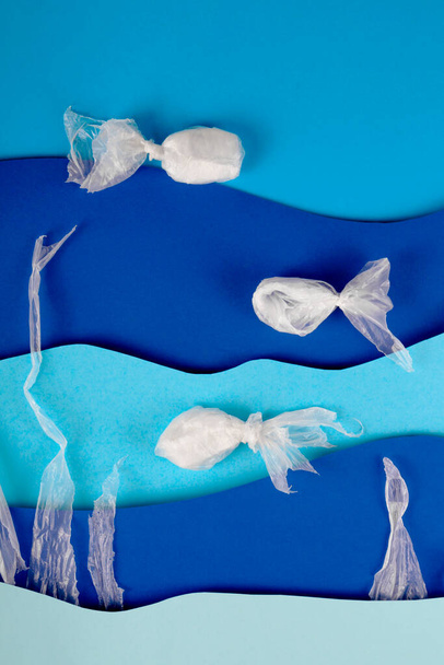 Blue background paper art sea waves with plastic fish. Ocean pollution - Photo, Image