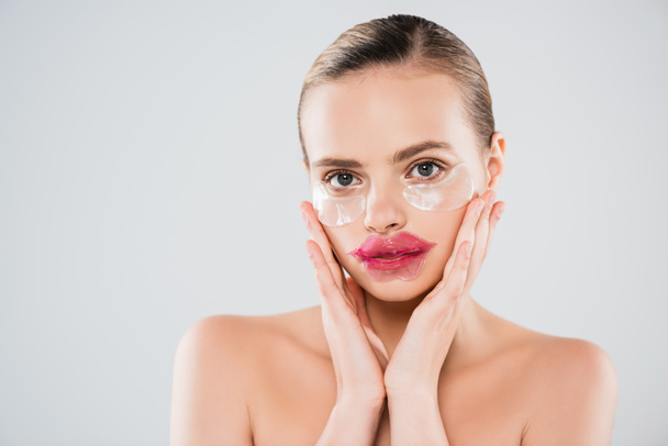naked woman with lip mask and eye patches touching clean face isolated on grey - Photo, Image