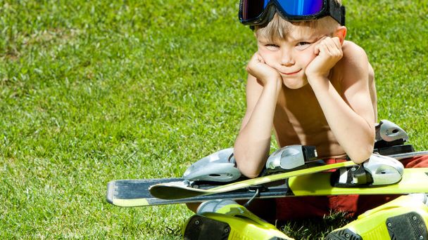 Funny little skier with ski on a green grass. Concept of active healthy lifestyle and waiting for the winter - Fotoğraf, Görsel