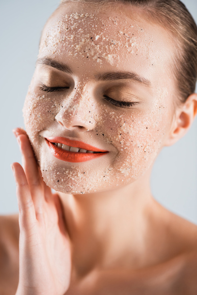 close up of happy young woman applying scrub isolated on white - Fotografie, Obrázek