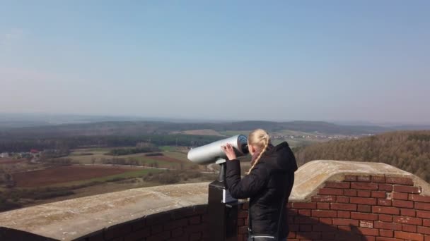 Attraktive Reiseleiterin sucht mit Fernglas Tal in der Nähe der alten Burg ab - Filmmaterial, Video