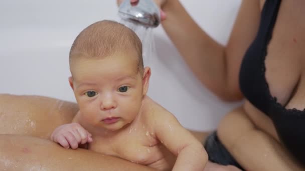 Newborn baby girl is taking bath in bathroom at home. Hygiene and health care for newborn baby. - Felvétel, videó