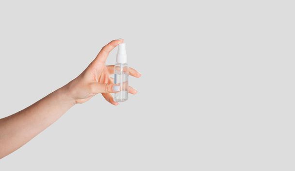 Contagious disease protection. Female hand holding bottle of sanitizer on white background, copy space - Foto, Imagen