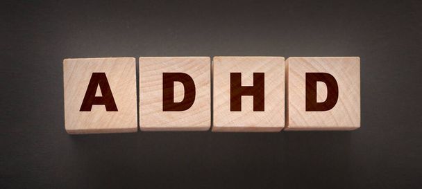 ADHD - медична концепція. Розлад гіперактивності дефіциту уваги. Дерев'яні кубики на чорному
 - Фото, зображення