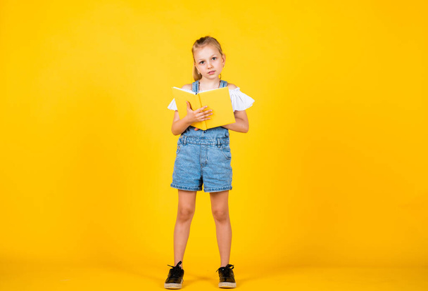 my childhood memories. Back to school and childhood concept. Pupil on yellow background. Kid with smart look and casual outfit. modern education concept. inspired with idea. Girl read the book - Фото, изображение