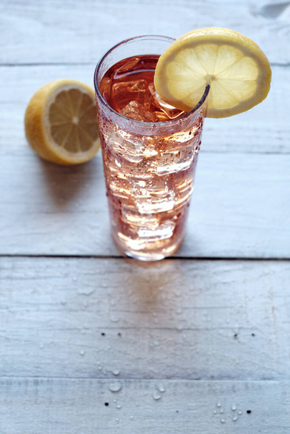 Cam tüpte kırmızı çay dondurması ve bir dilim limon. - Fotoğraf, Görsel
