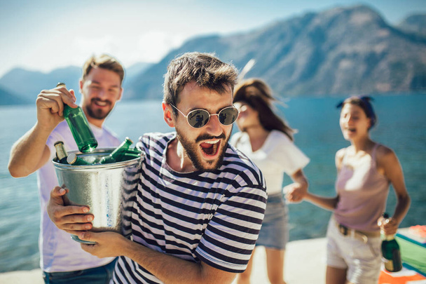 Группа друзей, тусующихся с пивом на пляже - Фото, изображение