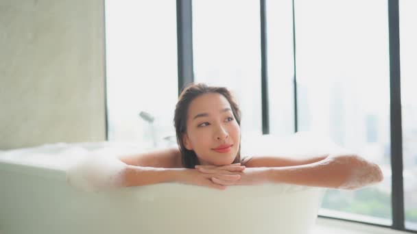 metraje de hermosa joven mujer asiática tomando baño con espuma en casa - Metraje, vídeo