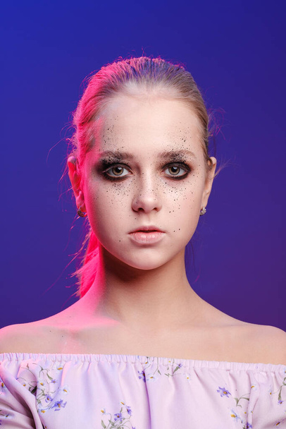 Close-up portrait of a young girl 20-25 years old with eye makeup on a bright modern neon background.  - Foto, Imagem