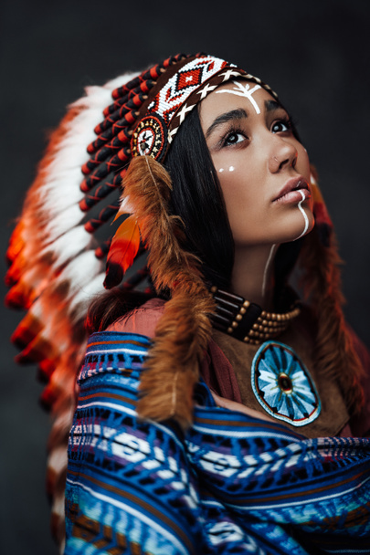 Close up retrato de uma jovem mulher indiana americana atraente com maquiagem em chapéu de pena tradicional e roupas
 - Foto, Imagem
