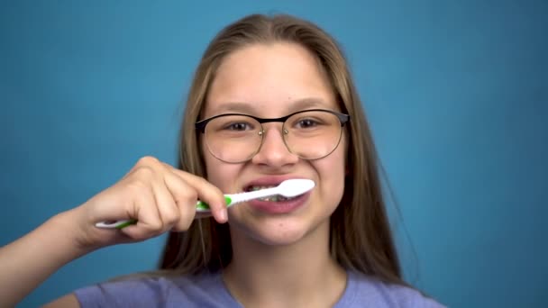 Fille avec bretelles brosser ses dents avec une brosse à dents gros plan. Une fille avec des accolades colorées sur ses dents garde ses dents propres. - Séquence, vidéo