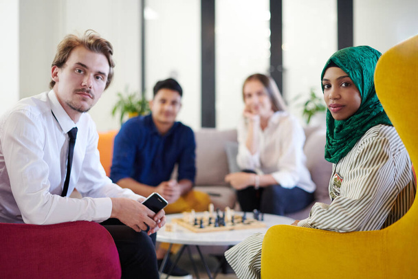 multiethnic group of business people playing chess while having a break in relaxation area at modern startup office - Foto, afbeelding