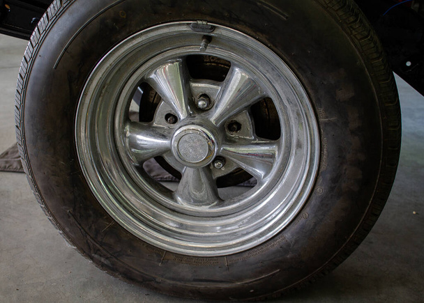 Foto eines Muscle Cars, das restauriert werden soll. Der Reifen und die Originalfelge sind im Lieferumfang enthalten. - Foto, Bild