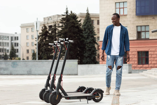 Guy standing and looking at rental motorized kick scooters - Photo, Image