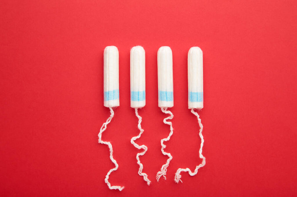 Menstrual tampon on a red background. Cotton tampon for women. Top view - Zdjęcie, obraz