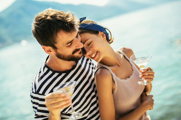 若いですカップルでワインを持っていますロマンチックなデートオンザビーチ - 写真・画像