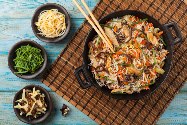 Rice noodles with chicken, mushrooms mun and vegetables, prepared in wook. Top view. - Foto, Imagen