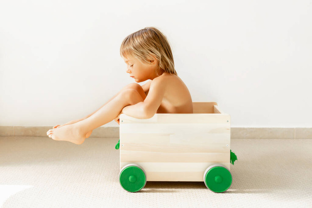 Sad baby boy in a toy box on a white background. - Photo, Image