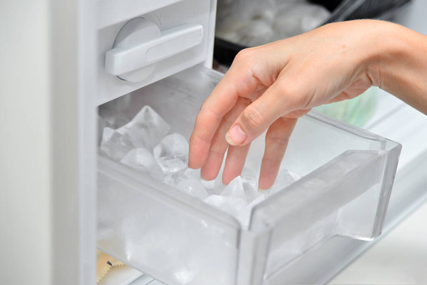 Baarimikko avaa jääpalan ja ottaa sen jääpalakoneesta. - Valokuva, kuva