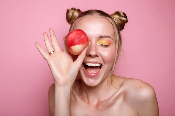 Girl with peach smiles on pink background. Healthy smile - Photo, Image