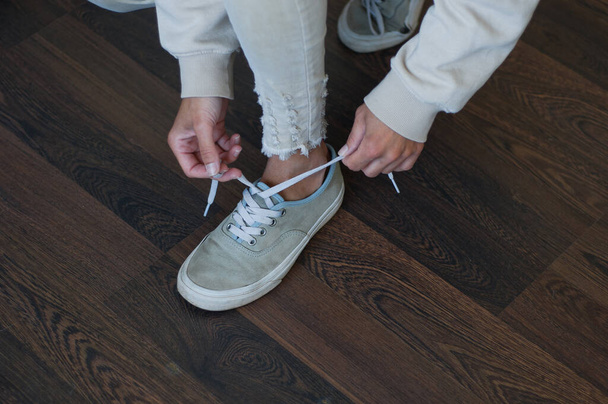 Καλλιεργημένη φωτογραφία γυναίκας να δένει αθλητικά παπούτσια πριν την προπόνηση - Φωτογραφία, εικόνα