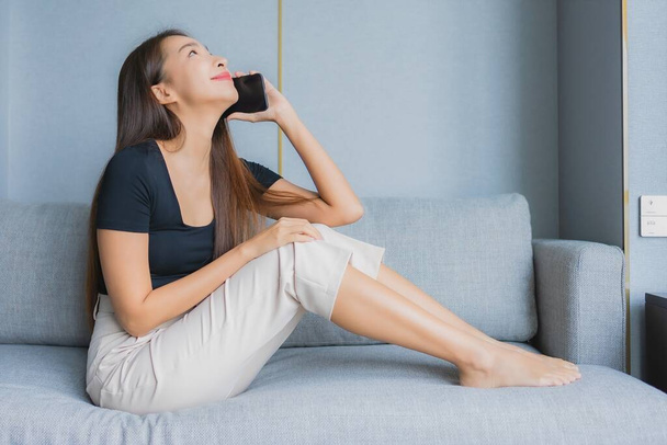 Ritratto bella giovane donna asiatica uso smart cellulare sul divano in soggiorno - Foto, immagini