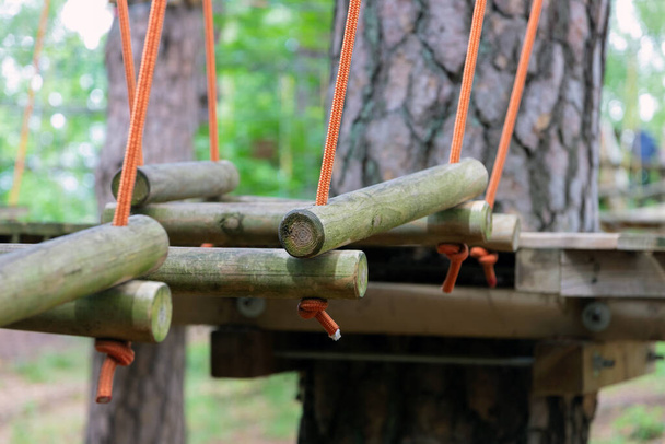 Eine Brücke aus an Seilen gebundenen Baumstämmen, Teil des Seilweges. Extremsport. - Foto, Bild