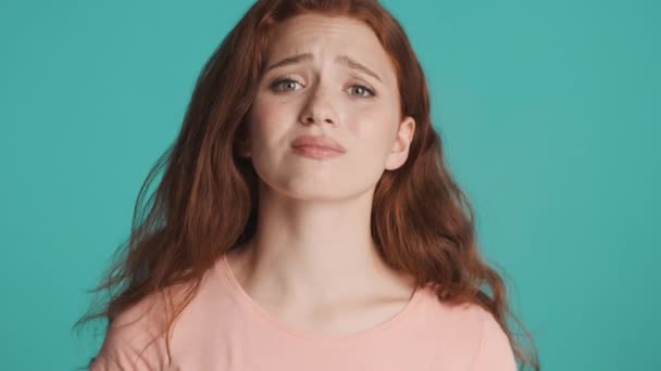 Houkutteleva hermostunut punapää tyttö ujostelee kameran yli värikäs tausta - Materiaali, video