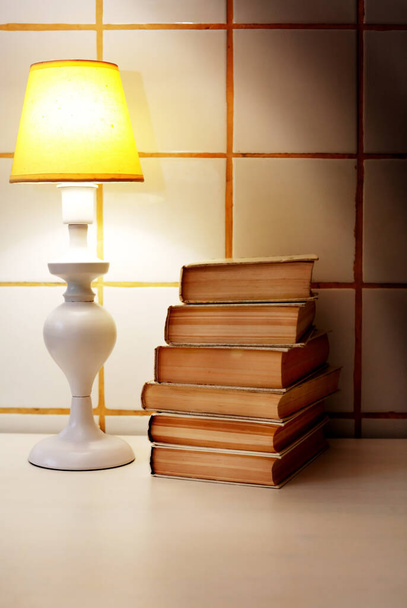Elegance valkoinen pöytävalaisin keltainen lampunvarjostin lähellä pino kirjoja - Valokuva, kuva