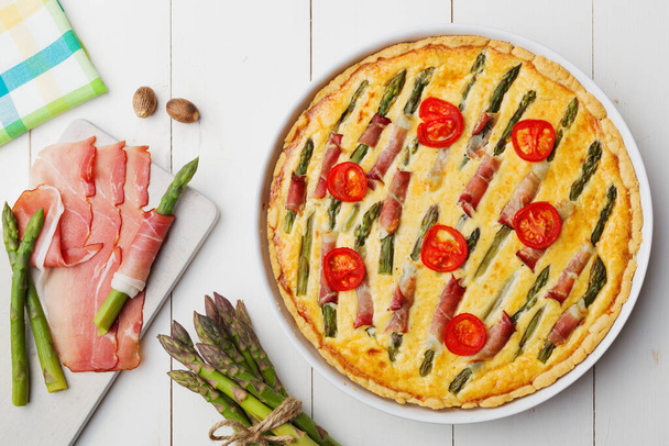 Tart with asparagus and tomatoes on white wooden background. - Fotografie, Obrázek