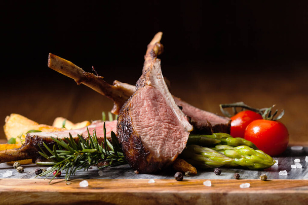 Baked lamb loin, served with asparagus. Dark background. - 写真・画像
